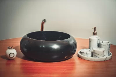 Elegant Black Bathroom Sink with Marble-Finished Soap Dispenser and Unique Apple-Shaped Clock